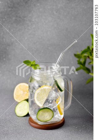 mason jar of cold detox water with cucumber and lemon or lemonade on grey background 103107763