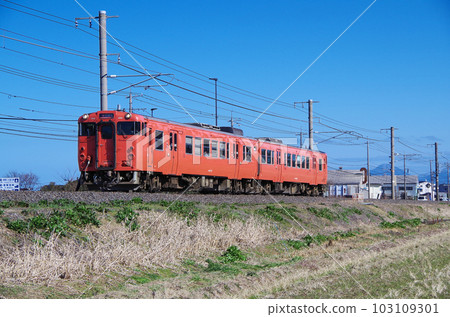 午後，開往出雲市的朱紅色柴油列車在山陰本線上行駛。 103109301
