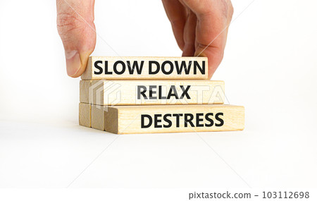 Destress symbol. Concept words Slow down Relax Destress on wooden blocks. Beautiful white table white background. Doctor hand. Psychological business slow down Relax destress concept. Copy space. 103112698