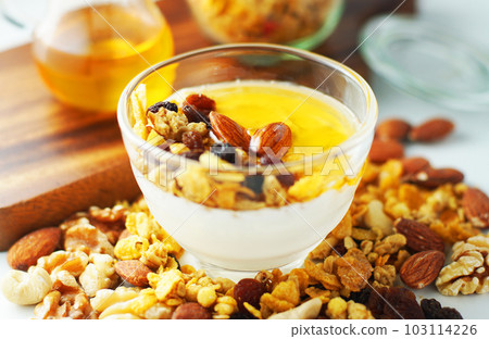Spread granola on yogurt and sprinkle with honey. 103114226