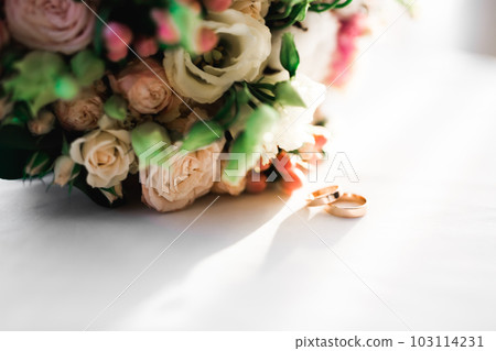 Beautiful toned picture with wedding rings against the background of a bouquet of flowers Beautiful toned picture with wedding rings against the background of a bouquet of flowers 103114231
