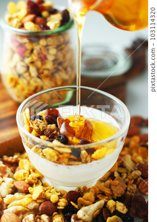 Spread granola on yogurt and sprinkle with honey. Spread granola on yogurt and sprinkle with honey. 103114320