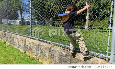 child playing on fence in park child playing on fence in park 103115772