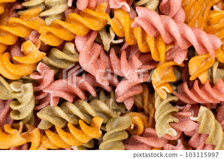 Rice vegetable pasta in the form of spirals, top view. Healthy rice pasta with tomatoes, selenera, carrots and beets 103115997