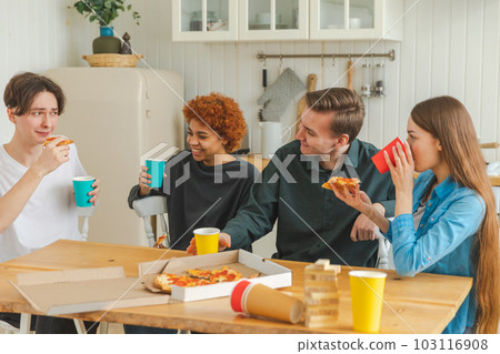Home party. Friends spending time together having fun laughing communicating at home. Happy diverse group eating pizza drinking beer or lemonade. Mixed race young buddies best friends enjoying weekend Home party. Friends spending time together having fun laughing communicating at home. Happy diverse group eating pizza drinking beer or lemonade. Mixed race young buddies best friends enjoying weekend 103116908