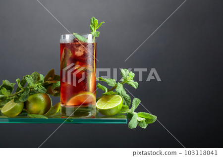 Cuba Libre with brown rum, cola, mint, and lime on a black background. Cuba Libre with brown rum, cola, mint, and lime on a black background. 103118041