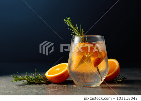 Cocktail gin tonic with ice, rosemary, and orange on a stone table. Cocktail gin tonic with ice, rosemary, and orange on a stone table. 103118042