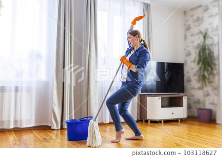 Happy young woman with mop singing, dancing and having fun while cleaning floor 103118627