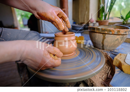ceramics, workshop, ceramic art concept - close-up of man's hands forming a new vessel, man's fingers working with potter's wheel and raw edge, frontal close-up. 103118802
