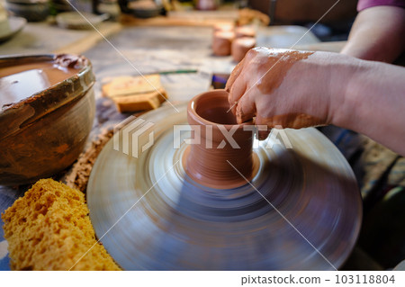 ceramics, workshop, ceramic art concept - close-up of man's hands forming a new vessel, man's fingers working with potter's wheel and raw edge, frontal close-up. 103118804