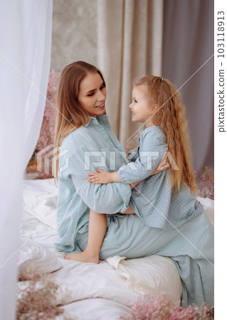 Mom and little daughter in blue pajamas are hugging Mom and little daughter in blue pajamas are hugging 103118913