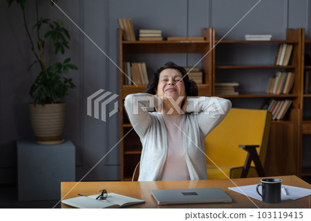 Middle aged senior woman at home relaxing stretching hands and body taking break from work on laptop. Older mature woman happy after work done satisfied by good result. Fatigue from long laptop usage Middle aged senior woman at home relaxing stretching hands and body taking break from work on laptop. Older mature woman happy after work done satisfied by good result. Fatigue from long laptop usage 103119415