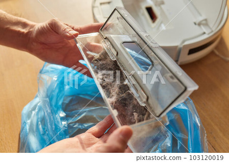 Cleaning the filter of the vacuum robot cleaner from dirt, close-up. 103120019