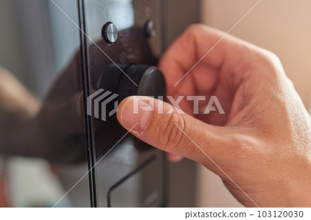 Hand pushing button of microwave oven for cooking food in kitchen 103120030