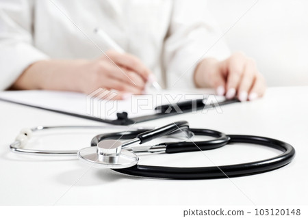 Phonendoscope on the background of a doctor who fills out a questionnaire for a new patient Phonendoscope on the background of a doctor who fills out a questionnaire for a new patient 103120148
