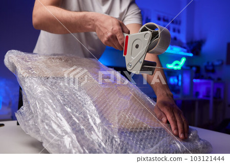 young man packing a monitor in a cardboard box. 103121444