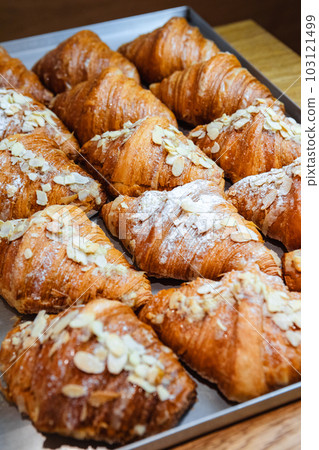Sprinkle the finished croissants on a baking sheet with almond flakes and powdered sugar 103121499