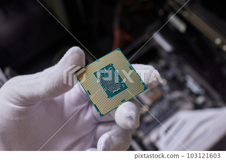 Hand in white glove holding a CPU computer processor microchip. 103121603