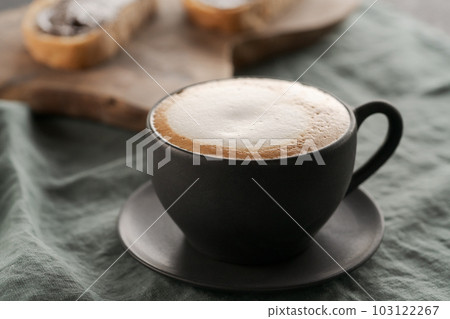 Cappuccino in black cup with ciabatta slices with chocolate spread on background Cappuccino in black cup with ciabatta slices with chocolate spread on background 103122267