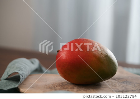 Whole ripe red mango on olive wood board 103122784