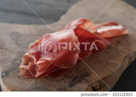 bresaola slices on olive wood board 103122881