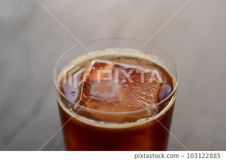 Closeup espresso tonic with clear ice cube in tumbler glass on oak wood table Closeup espresso tonic with clear ice cube in tumbler glass on oak wood table 103122885