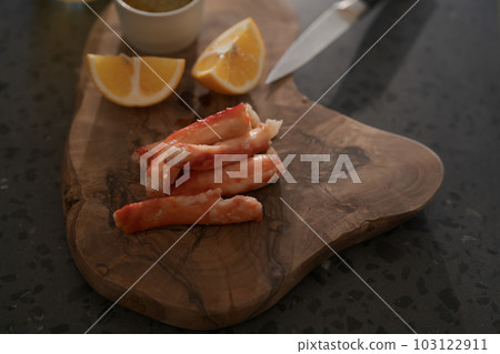 Crab legs with lemon and dressing on olive woob board Crab legs with lemon and dressing on olive woob board 103122911