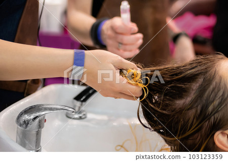 Woman hair stylist washing customers hair at hairdressing salon - close up Woman hair stylist washing customers hair at hairdressing salon - close up 103123359