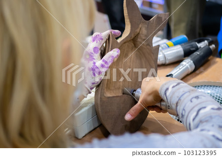 Woman carpenter using hand rotary tool, polishing wood product 103123395
