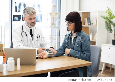Physician measuring pulse of female by wearable tonometer 103124473