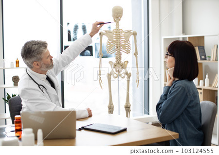 Doctor showing injury site to patient using skeleton Doctor showing injury site to patient using skeleton 103124555
