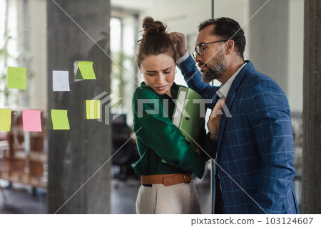 Mature man abusing his younger colleague, concept of harassment at workplace. 103124607