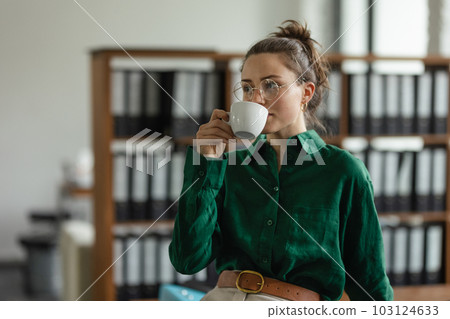 Portrait of young woman with cup of coffee in office. 103124633