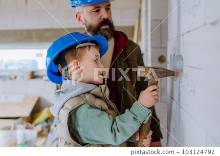 Father and his little son working on their unfinished house. 103124792
