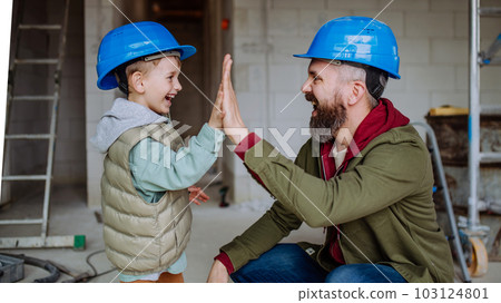 Father and his little son working on their unfinished house. 103124801