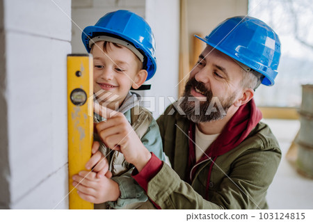 Father and his little son working on their unfinished house. 103124815