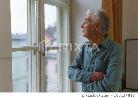 Senior man looking out of window, concept of solitude in retirement. Senior man looking out of window, concept of solitude in retirement. 103124918
