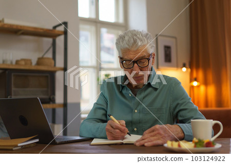 Senior man writing notes in his diary. 103124922