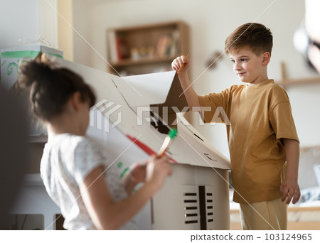 Happy children painting handmade carboard house together. Happy children painting handmade carboard house together. 103124965
