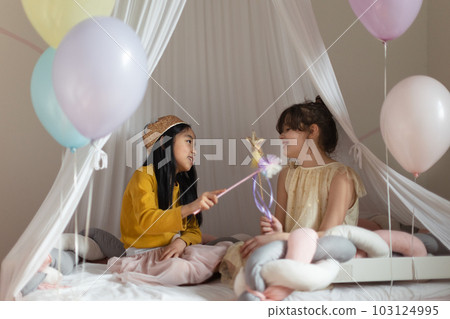 Happy girls playing princess with princess wands in a play tent. Happy girls playing princess with princess wands in a play tent. 103124995