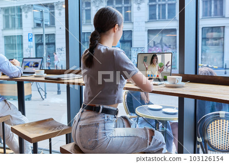 Virtual video chat of teenage girls friends, using laptop in cafe Virtual video chat of teenage girls friends, using laptop in cafe 103126154