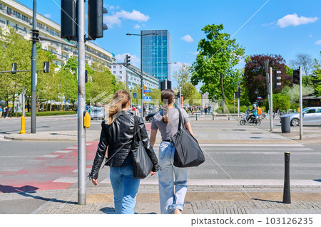 Young women cross the road at pedestrian crossing, in modern European city 103126235