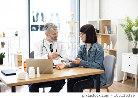 Therapist greeting patient with numbers shown on tonometer 103126359