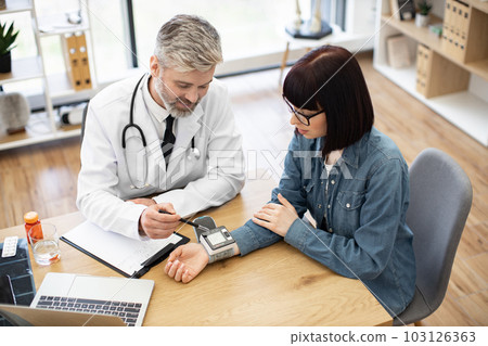 Physician and woman monitoring tonometer on wrist in office 103126363