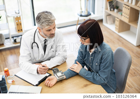 Physician and woman monitoring tonometer on wrist in office 103126364