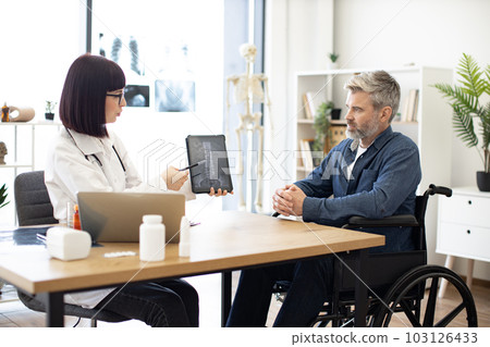 Traumatologist reassuring male patient using spine scans 103126433
