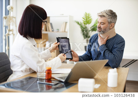 Radiologist showing CT scan picture to patient in clinic Radiologist showing CT scan picture to patient in clinic 103126438
