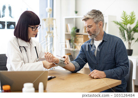 Cute female doctor removing tonometer from patient's wrist 103126484