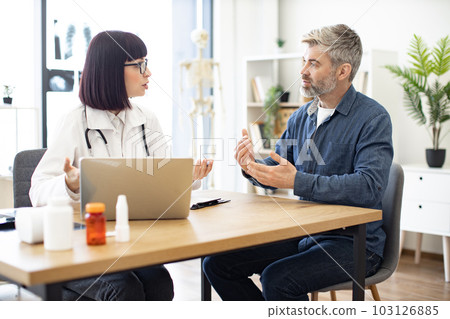 Doctor and patient discussing symptoms of illness in clinic 103126885