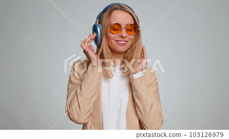 Happy business woman in headphones listening music dancing disco having fun relaxing on party Happy business woman in headphones listening music dancing disco having fun relaxing on party 103126979